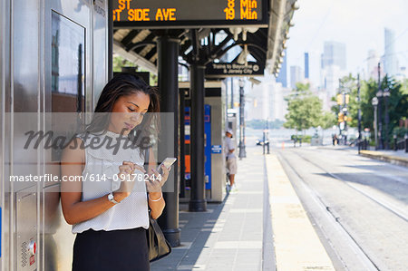 Businesswoman using cellphone by ticket machine