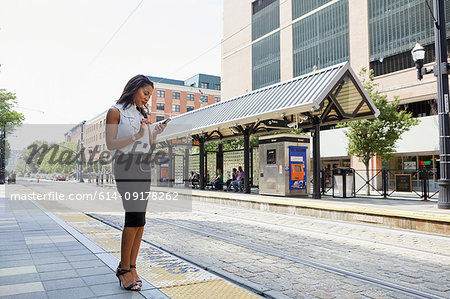 Businesswoman using cellphone in light rail station