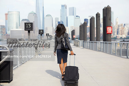 Businesswoman with wheeled luggage on ferry pier