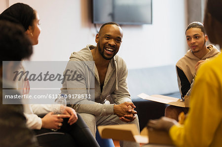 Smiling male mentor talking to teenagers in youth organization