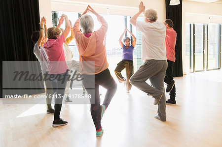 Active seniors exercising, practice yoga tree pose in circle