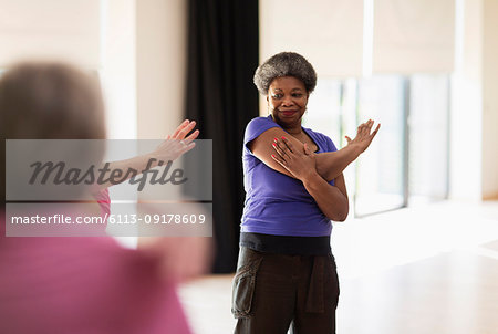 Smiling active senior stretching arm in exercise class