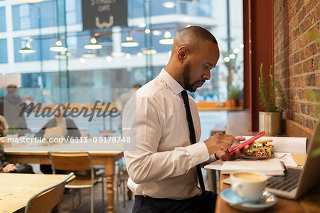 Businessman using smart phone and eating lunch in cafe