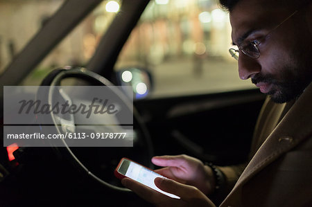 Man using smart phone in car at night