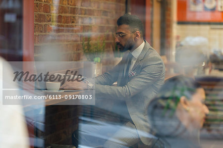 Businessman working at laptop in cafe