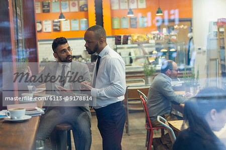 Businessmen using laptop, working in cafe