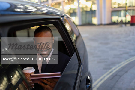 Businessman drinking coffee and using digital tablet in crowdsourced taxi