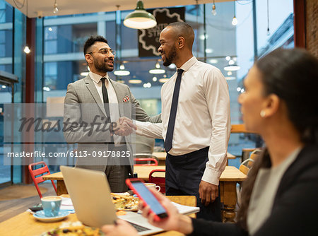Businessmen handshaking, working in cafe
