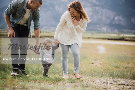 Parents walking with baby son in rural field