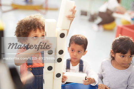 Curious kids stacking large dominos at interactive exhibit in science center