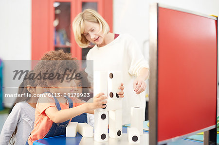 Teacher and curious students stacking large dominos in science center