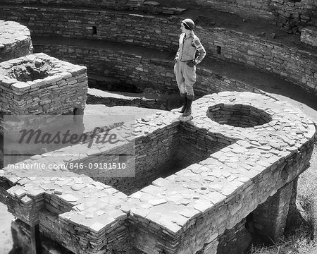 1930s WOMAN STANDING ON LARGE KIVA CHACO CANYON PUEBLO RUINS NEW MEXICO USA