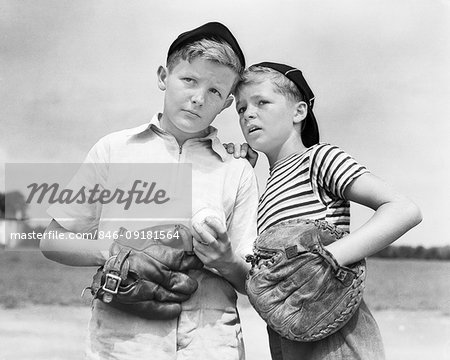 1930s TWO BOYS WEARING BASEBALL CAPS AND GLOVES CATCHER AND PITCHER PLANNING STRATEGY WHISPERING