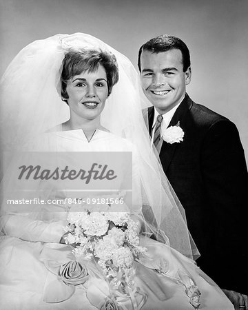 1960s PORTRAIT OF HAPPY SMILING BRIDE AND GROOM IN WEDDING CLOTHES LOOKING AT CAMERA