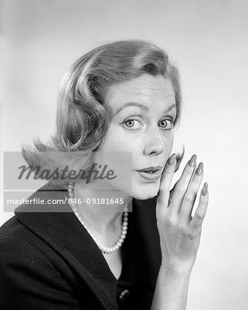 1950s 1960s WOMAN LOOKING AT CAMERA WHISPERING SECRET GOSSIP WITH HAND UP TO MOUTH