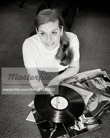 1960s FASHIONABLE YOUNG WOMAN LOOKING UP HOLDING 33 RPM VINYL RECORD ALBUM