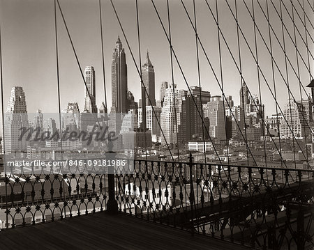 1950s SKYLINE LOWER MANHATTAN SEEN THRU CABLES OF BROOKLYN BRIDGE NEW YORK CITY NY USA