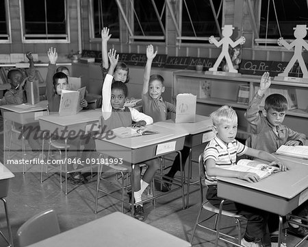 1960s ELEMENTARY CLASSROOM STUDENTS LOOKING AT CAMERA ALL BUT ONE EAGERLY RAISING THEIR HAND