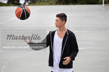 Male teenage basketball player on basketball court throwing and catching ball