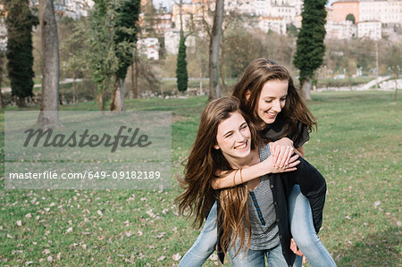 Girlfriends playing piggyback ride in park