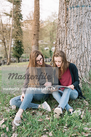 Girlfriends reading book in park