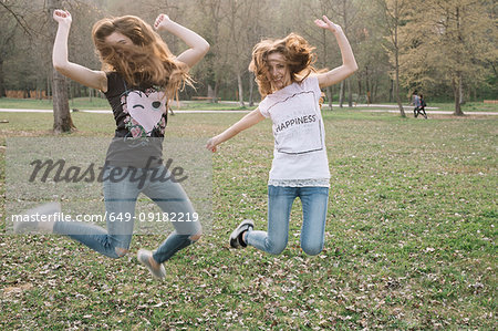 Happy girlfriends jumping for joy in park