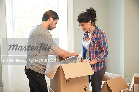 Couple packing mirror into cardboard box