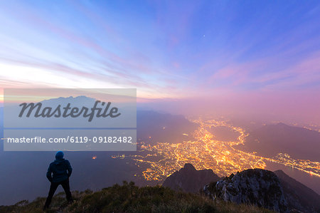 Hiker on Monte Coltignone looks toward Monte Resegone and Lecco at dawn, Lombardy, Italian Alps, Italy, Europe