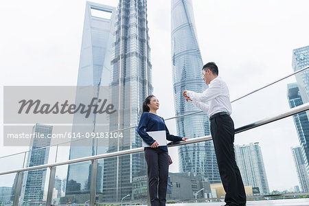 Young businesswoman and man talking in city financial district, Shanghai, China