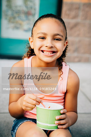 Smiling girl sitting on steps eating ice cream