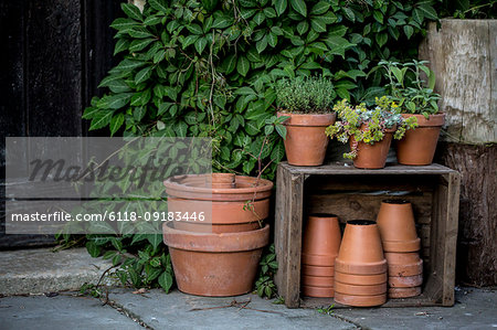 Close up of stacks of terracotta flower pots on a stone floor and wooden box.