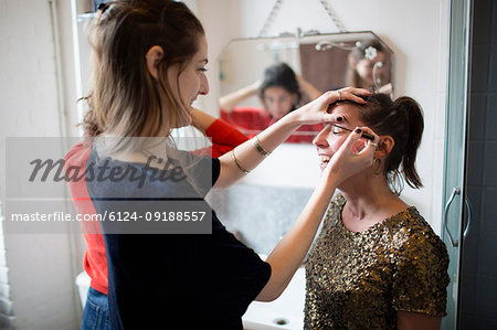 Young women getting ready, applying makeup in bathroom