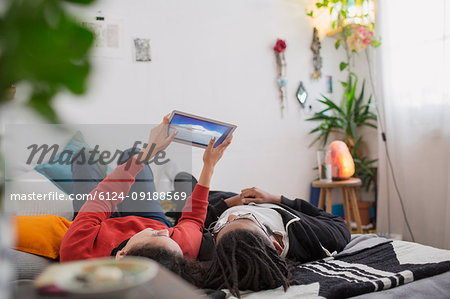 Young couple relaxing, using digital tablet on bed