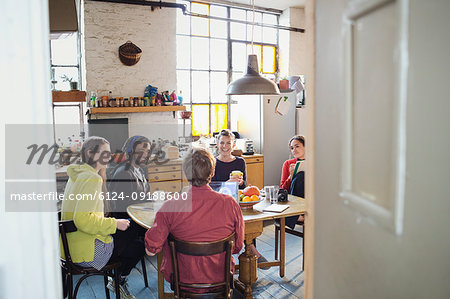 Young roommate friends at breakfast table in apartment kitchen