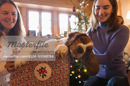 Mother and daughter playing with dog in Christmas gift box