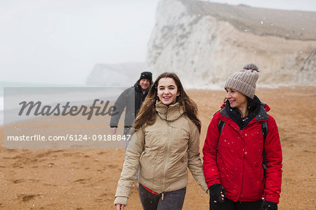 Affectionate mother and daughter walking on snowy winter beach