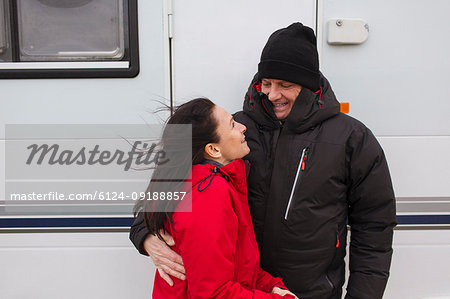 Affectionate couple in warm clothing hugging outside motor home