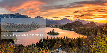 Elevated view of lake Bled at sunrise. A young woman admires the view. Bled, Upper Carniola, Slovenia