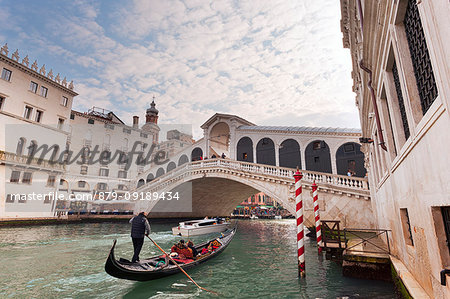 A traditional venetian gondola on Grand Canal, under Rialto Bridge, Venice, Veneto, Italy