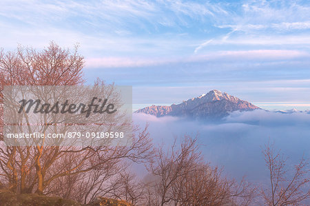 Foggy sunrise from the top of Monte Barro, with the Grignetta in the background. Monte Barro Regional Park, Brianza, Lombardy, Italy, Europe.