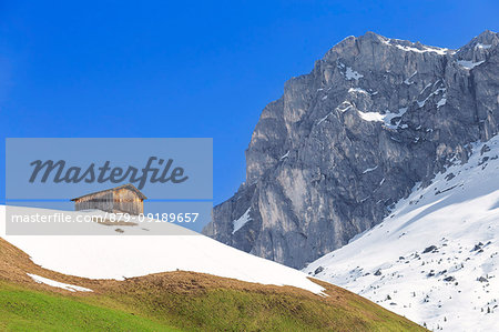 Typical hut during spring thaw in Partnun with Ratikon mountain range in the background. Partnun, Prattigau valley, District of Prattigau/Davos, Canton of Graubünden, Switzerland, Europe.