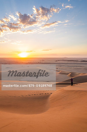 Man admiring the sunrise from the sand dunes,Walvis Bay,Namibia,Africa Man admiring the sunrise from the sand dunes,Walvis Bay,Namibia,Africa
