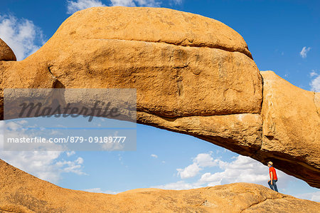 Tourist admires the view through the rock arch,Spitzkoppe,Damaraland,Namibia,Africa