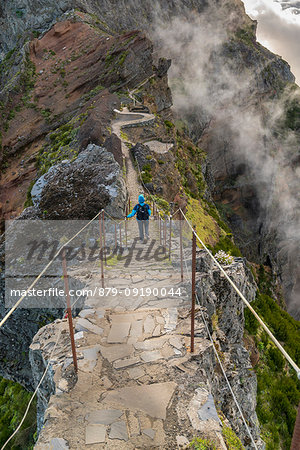 Hiker descending the steps on Vereda do Areeiro, the trail that links Pico Ruivo to Pico do Arieiro, Funchal, Madeira region, Portugal.