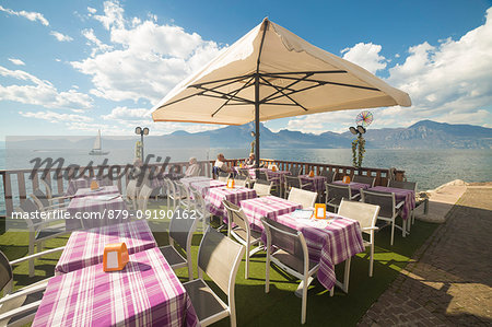 Tables of a little restaurant on the lakefront of Torri del Benaco on the eastern shore of Lake Garda, Verona province, Veneto, Italy.