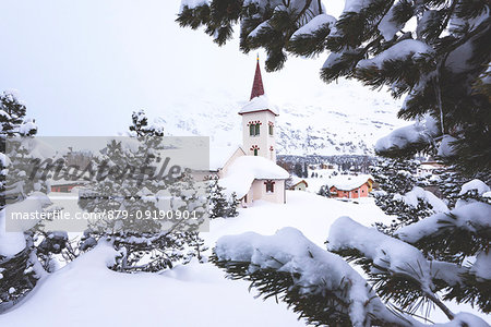 Snowy landscape and the typical church Maloja Canton of Graubünden Engadine Switzerland Europe