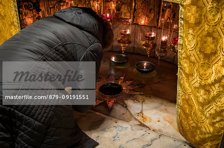 Pilgrim praying at the birthplace of Jesus Christ marked with a fourteen-point silver star, the Altar of the Nativity, Church of the Nativity, Bethlehem, Palestine, Middle East