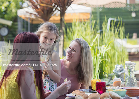Affectionate lesbian couple and daughter enjoying lunch on patio