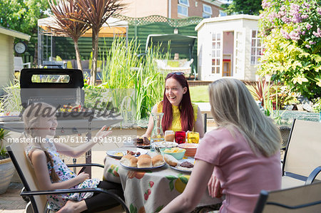 Lesbian couple and daughter enjoying barbecue lunch on summer patio