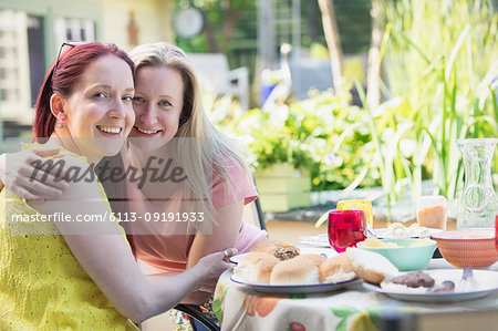 Portrait affectionate lesbian couple enjoying lunch on patio